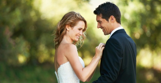 A beautiful bride adjusts her grooms suit as they stroll through the gardens