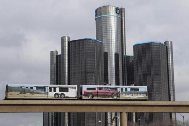 Two cars of the public rail are seen covered with a advertisement for 2014 Chevy Silverado pickup truck as they move past General Motors World Headquarters in Detroit